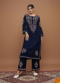 Woman wearing a navy blue embroidered outfit on a brown background