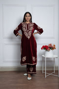 Woman wearing a maroon kurta set with white embroidery.